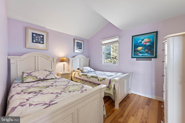 bedroom with baseboards, light wood finished floors, and lofted ceiling