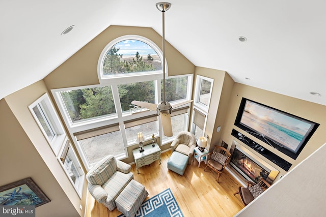 living room featuring a glass covered fireplace, wood finished floors, and vaulted ceiling