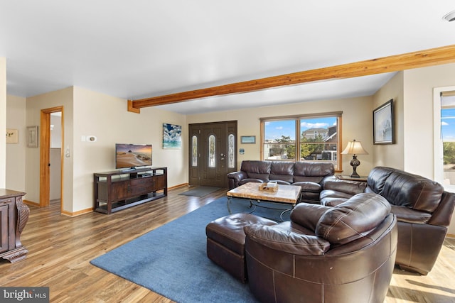 living room featuring baseboards, light wood finished floors, and beam ceiling