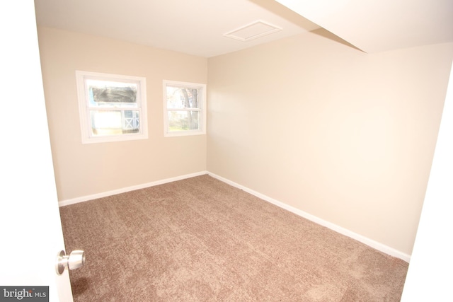 spare room with attic access, baseboards, and carpet