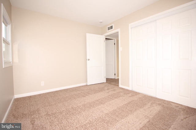 unfurnished bedroom with carpet floors, baseboards, visible vents, and a closet