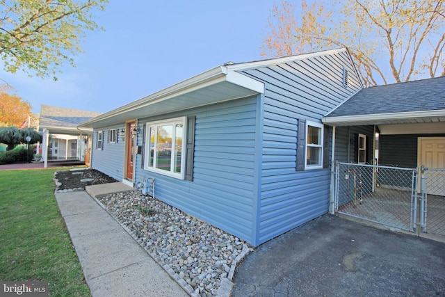 view of side of home with a yard and a gate