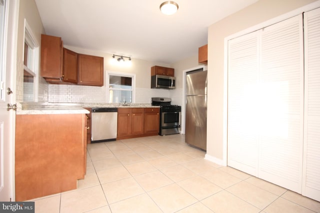 kitchen featuring light tile patterned floors, appliances with stainless steel finishes, and brown cabinetry
