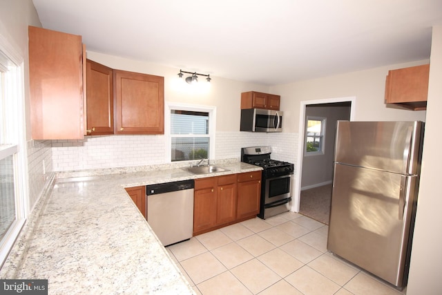 kitchen with light countertops, brown cabinets, a sink, backsplash, and stainless steel appliances