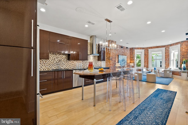 kitchen featuring dark brown cabinetry, visible vents, appliances with stainless steel finishes, a sink, and extractor fan