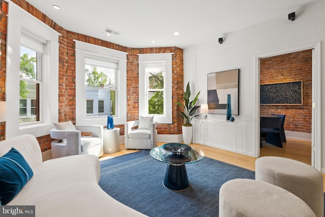 living area featuring wood finished floors, recessed lighting, brick wall, and visible vents