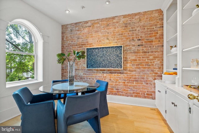dining area with brick wall and light wood finished floors