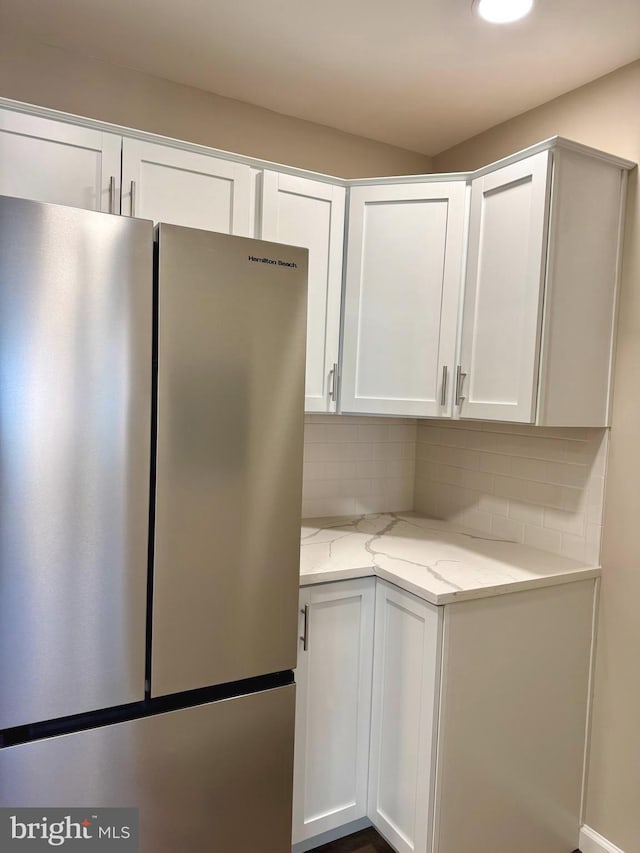 511 N Armistead St Unit T2, Alexandria, VA 22312 - kitchen featuring light stone counters, white cabinets, freestanding refrigerator, and backsplash