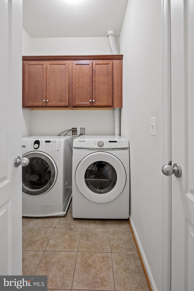 clothes washing area featuring light tile patterned floors, washing machine and dryer, and cabinet space