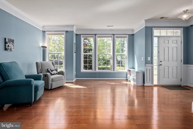 foyer with visible vents, ornamental molding, and hardwood / wood-style floors