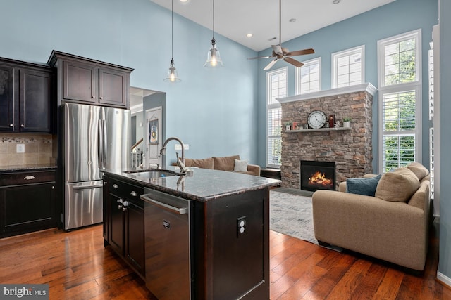 kitchen featuring a high ceiling, appliances with stainless steel finishes, a sink, dark stone countertops, and open floor plan