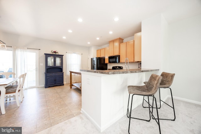 kitchen with light brown cabinetry, a peninsula, recessed lighting, and black appliances
