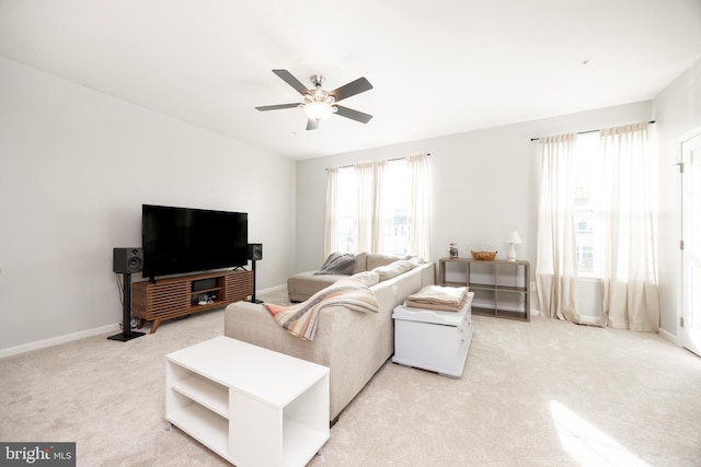 living room featuring baseboards, a ceiling fan, and light colored carpet