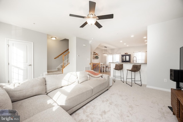 living room with light colored carpet, a ceiling fan, baseboards, recessed lighting, and stairway