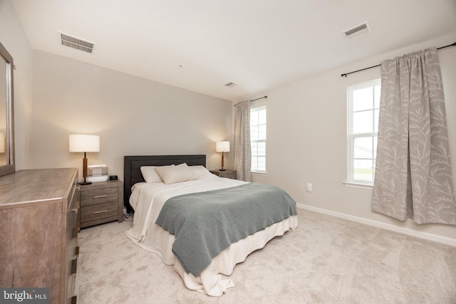 bedroom with baseboards, light colored carpet, and visible vents