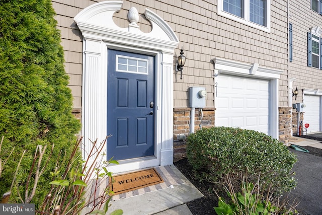 property entrance with an attached garage and stone siding