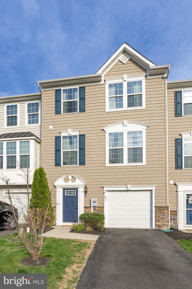 townhome / multi-family property featuring an attached garage and aphalt driveway