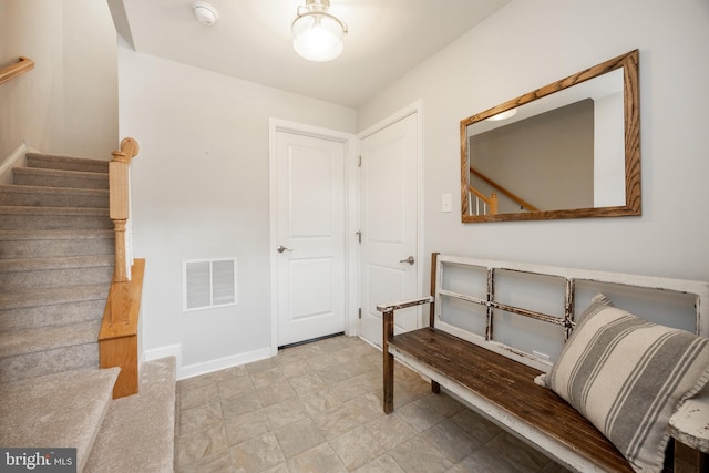 foyer with stairs, baseboards, and visible vents
