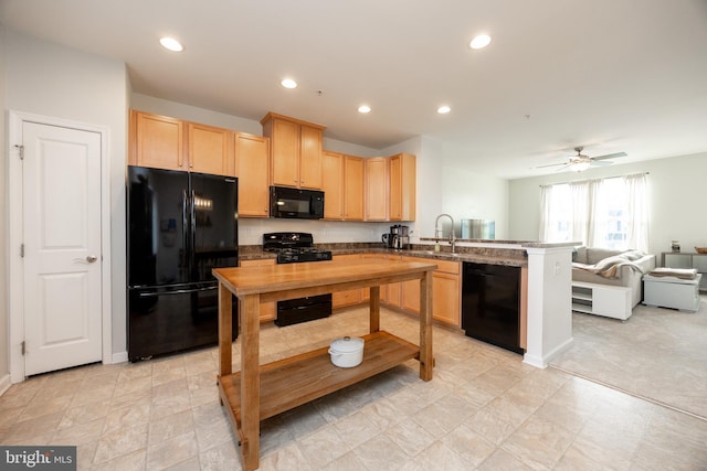 kitchen with light brown cabinetry, black appliances, a peninsula, and open floor plan