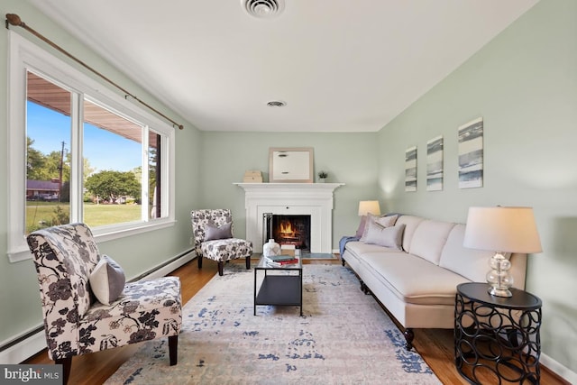 26105 Cornor Dr, Damascus, MD 20872 - living room with a warm lit fireplace, a baseboard heating unit, wood finished floors, and baseboards