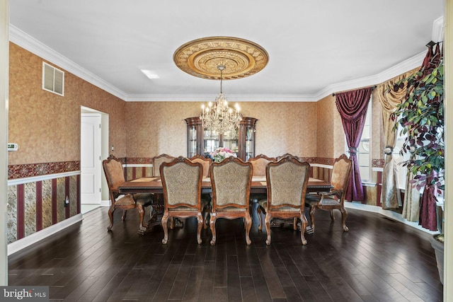 dining room featuring visible vents, wood-type flooring, crown molding, wallpapered walls, and a notable chandelier