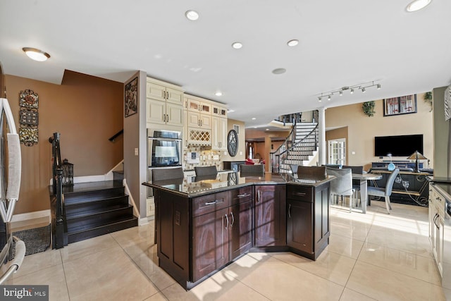 kitchen with dark stone counters, a center island, light tile patterned flooring, and cream cabinetry