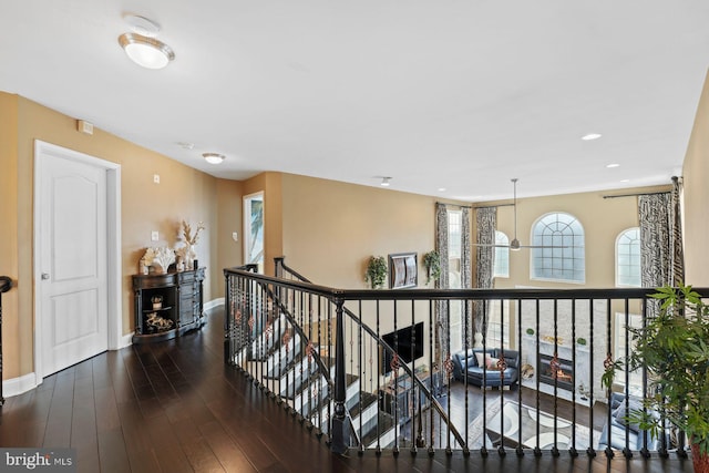 hallway with recessed lighting, baseboards, an upstairs landing, and wood finished floors