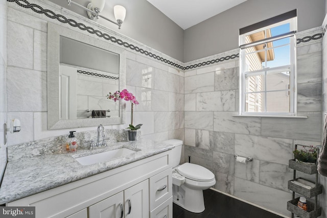 bathroom with vanity, wood finished floors, toilet, and tile walls