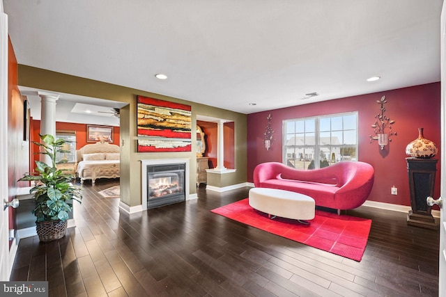 living room featuring ornate columns, recessed lighting, baseboards, and a glass covered fireplace