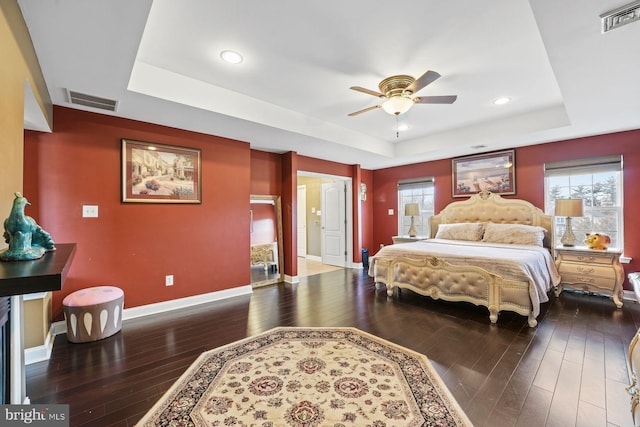 bedroom with a raised ceiling, baseboards, hardwood / wood-style floors, and visible vents