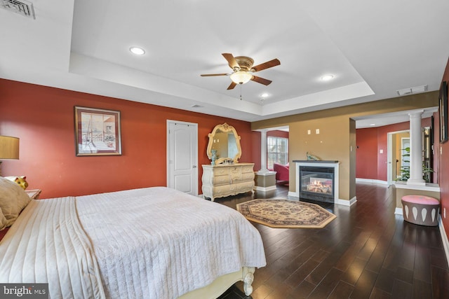 bedroom featuring a raised ceiling, baseboards, wood finished floors, and visible vents