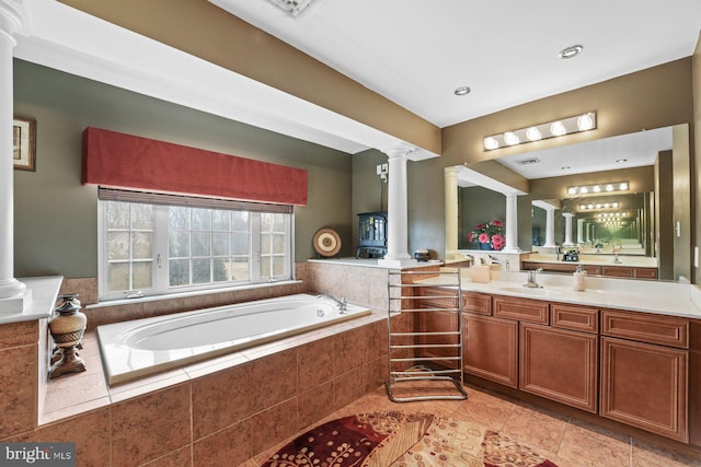 bathroom with tile patterned flooring, decorative columns, a garden tub, and vanity