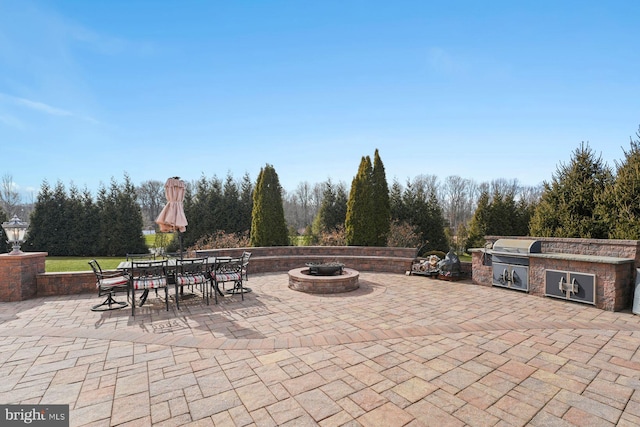 view of patio featuring an outdoor kitchen, outdoor dining space, and a fire pit