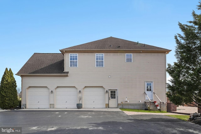 rear view of house featuring entry steps and driveway
