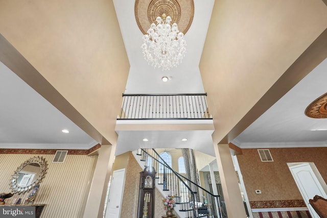 interior space featuring crown molding, wallpapered walls, an inviting chandelier, and visible vents