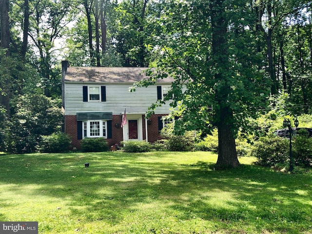 view of front of house with brick siding, a chimney, and a front lawn