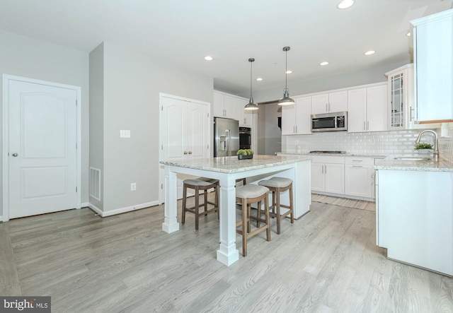 7928 Meridian Dr, Pasadena, MD 21122 - kitchen featuring appliances with stainless steel finishes, a sink, a breakfast bar area, a center island, and light wood-type flooring