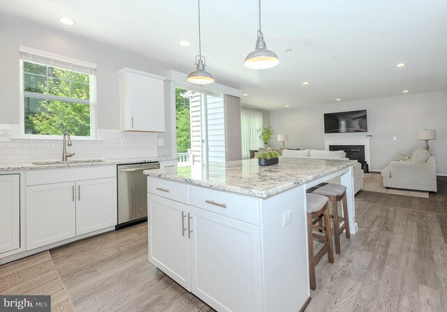 7928 Meridian Dr, Pasadena, MD 21122 - kitchen with dishwasher, a sink, light wood-type flooring, a kitchen island, and a fireplace