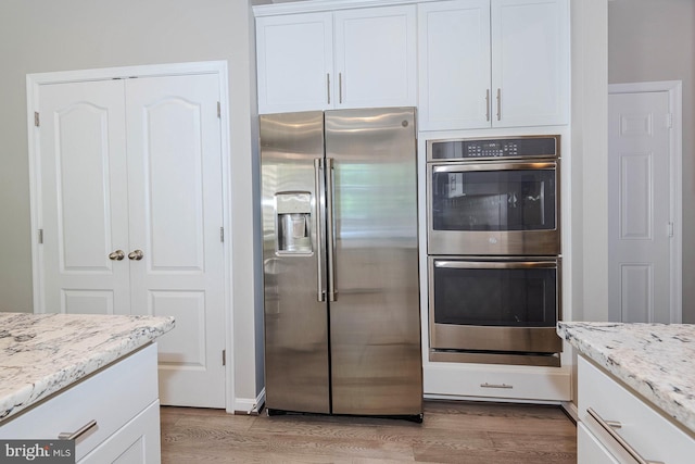 7928 Meridian Dr, Pasadena, MD 21122 - kitchen featuring appliances with stainless steel finishes, light wood-type flooring, white cabinets, and light stone counters