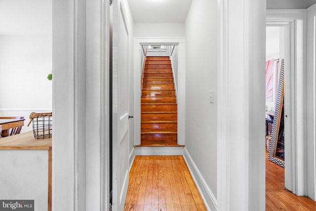 hallway with baseboards, stairs, and hardwood / wood-style floors