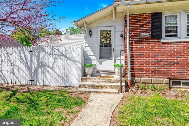 property entrance featuring brick siding and fence