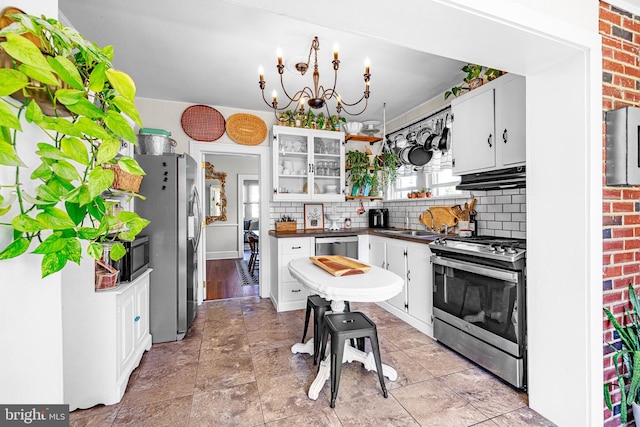 kitchen with decorative backsplash, dark countertops, under cabinet range hood, a sink, and stainless steel appliances