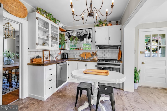 kitchen with dark countertops, extractor fan, a chandelier, stainless steel appliances, and tasteful backsplash