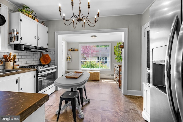 kitchen featuring crown molding, appliances with stainless steel finishes, baseboard heating, white cabinetry, and backsplash