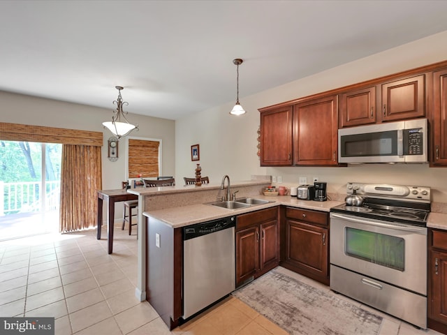 kitchen featuring appliances with stainless steel finishes, a sink, light countertops, a peninsula, and light tile patterned floors
