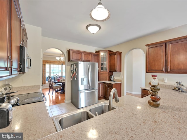 kitchen featuring arched walkways, a sink, glass insert cabinets, and stainless steel appliances