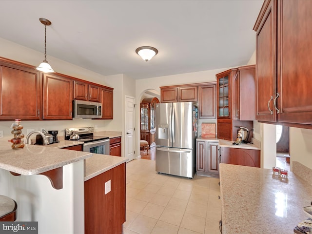 kitchen featuring appliances with stainless steel finishes, arched walkways, a kitchen breakfast bar, a peninsula, and glass insert cabinets