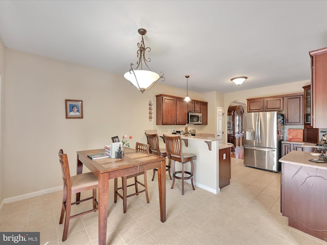dining room featuring light tile patterned floors, arched walkways, and baseboards
