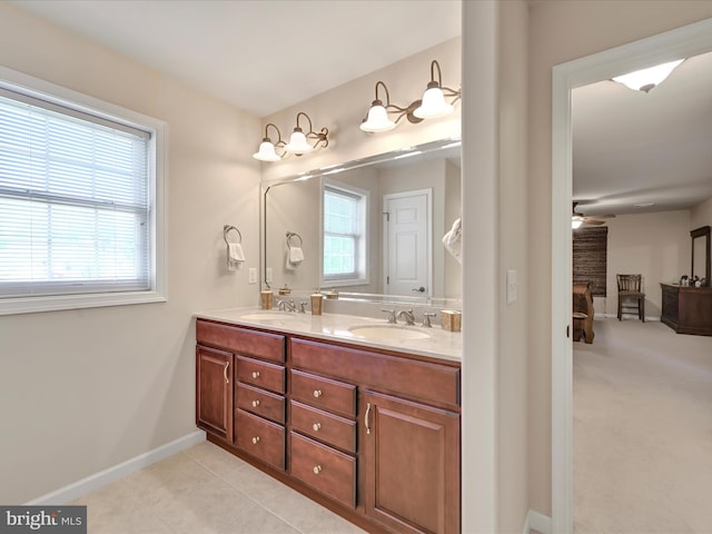 bathroom with double vanity, ceiling fan, a sink, baseboards, and ensuite bathroom