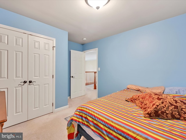 bedroom featuring baseboards, light carpet, and a closet
